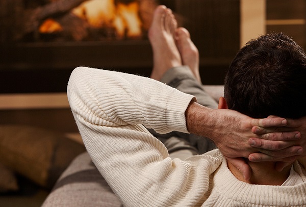 Foto einer Person, die auf einem Sofa vor einem Kachelofen von Hafnertec liegt